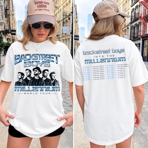 May include: A white t-shirt featuring a graphic print of the Backstreet Boys on the front with the text 'Backstreet Boys Millennium World Tour'. The back of the shirt displays the text 'Backstreet Boys Into The Millennium' and a list of tour dates.