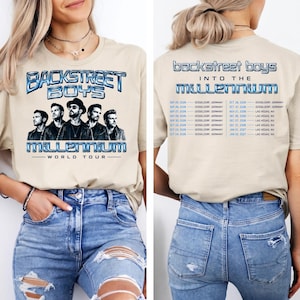 May include: A beige t-shirt featuring a Backstreet Boys Into the Millennium World Tour graphic on the front with a band portrait and metallic blue text. The back displays the tour title and a list of concert dates and locations in blue text.