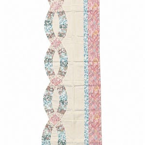 May include: A rectangular table runner featuring a cream-colored center panel. One side displays a scalloped edge with interlocking circular patterns in floral prints of pink, blue, and brown. The other side has vertical stripes of floral fabric.