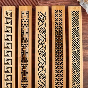 May include: Five rectangular bamboo incense holders arranged side by side. Each holder features a distinct laser-cut geometric or floral pattern along its center, showcasing the natural light tan wood grain and contrasting dark cutouts.