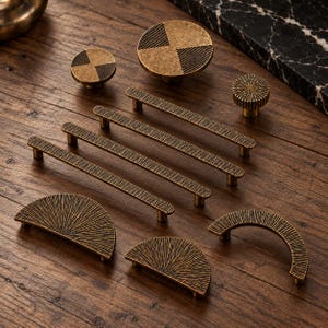 May include: A collection of antique brass cabinet hardware including three long bar pulls, two semi-circular pulls, two circular knobs with textured patterns, and one small round knob with a radial grooved design.