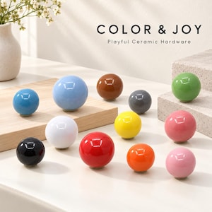 May include: A collection of round, glossy ceramic knobs in various solid colors including red, yellow, orange, pink, green, blue, light blue, white, black, gray, and brown. The text COLOR & JOY Playful Ceramic Hardware is visible.