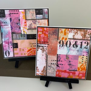 May include: Two small, colorful, abstract art pieces on easels. The art pieces are made of paper and have a patchwork design. The first piece has the numbers "78" and "12" on it. The second piece has the numbers "90 & 12" on it.