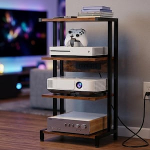 May include: A four-tier media storage rack with a black metal frame and brown wood-grain shelves. The unit holds a white game console, a white controller, a white projector, and a silver audio amplifier, with a power cord plugged into a wall outlet.