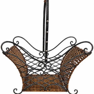 May include: A basket featuring a dark brown woven material base and sides, framed by a black metal structure with decorative scrollwork. The design includes a tall, central vertical handle secured with silver-toned rivets.