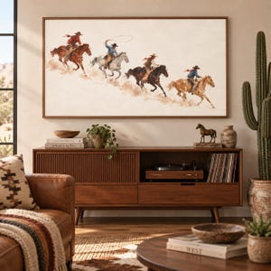 May include: A rectangular wall art print featuring a watercolor-style illustration of four cowboys riding horses across a dusty landscape. The scene depicts riders in motion, with one swinging a lasso, set against a light, neutral-toned background.