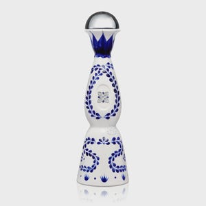 May include: A tall, white ceramic bottle with a rounded base and a slender neck, topped with a smooth, silver-coloured spherical cap. The bottle is decorated with intricate blue painted leaf patterns and a central floral emblem on the body.