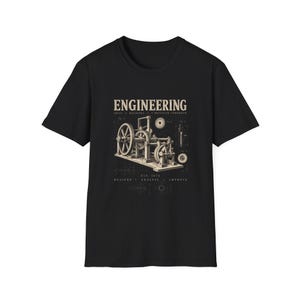 Könnte beinhalten: Ein schwarzes Kurzarm-T-Shirt mit einer beigen Grafik eines mechanischen Konstruktionsplans. Der Text lautet ENGINEERING, IDEAS, MACHINES, A BRIGHTER TOMORROW, EST. 1874, MEASURE, ANALYSE, IMPROVE, ergänzt durch technische Zahnrad-Illustrationen.