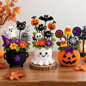 May include: Three crocheted Halloween arrangements in a black cauldron, a white ghost, and an orange pumpkin. The displays feature small crocheted figures including a black cat, bats, spiders, skulls, candy corn, and colorful flowers on green stems.