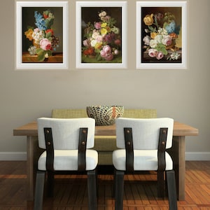 May include: Three framed floral still life paintings with white frames and a light brown background. The paintings feature bouquets of pink, white, and red flowers in a vase or basket.