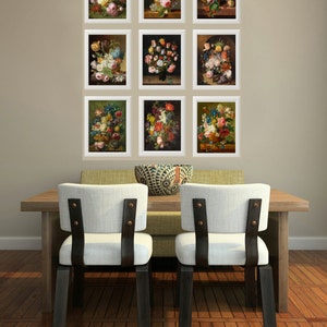 May include: Nine framed floral still life paintings with white frames are displayed on a beige wall above a wooden dining table with two chairs. The paintings feature a variety of colorful flowers, including roses, tulips, and lilies.