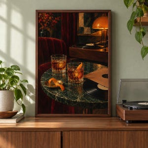 May include: A framed wall art print depicting a dark, moody interior scene with two glasses of amber liquid on a round green marble table. An orange peel garnish sits on a small plate, alongside a black vinyl record and a record player.