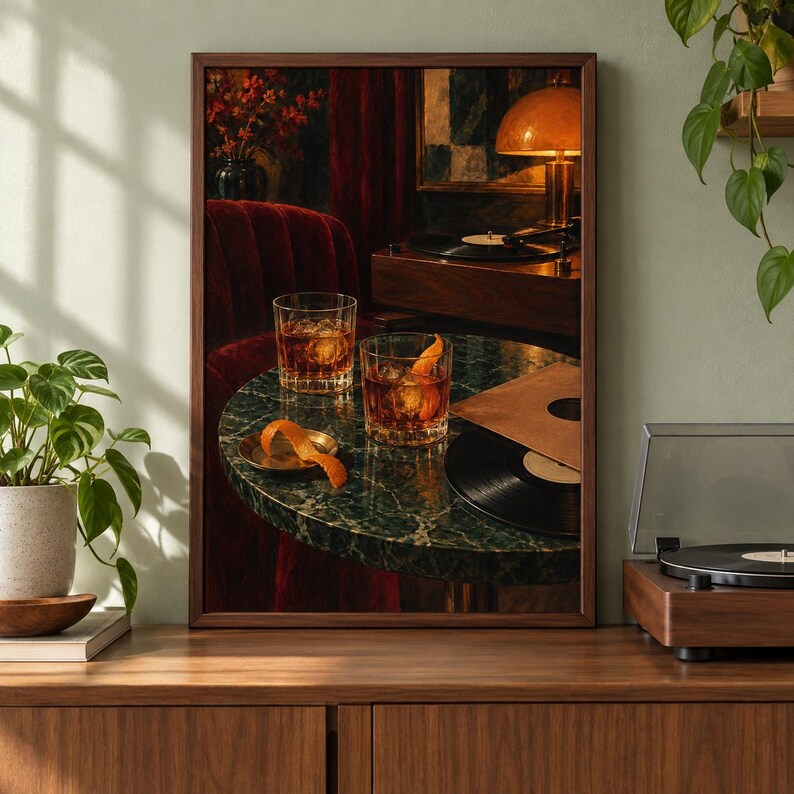 May include: A framed wall art print depicting a dark, moody interior scene with two glasses of amber liquid on a round green marble table. An orange peel garnish sits on a small plate, alongside a black vinyl record and a record player.