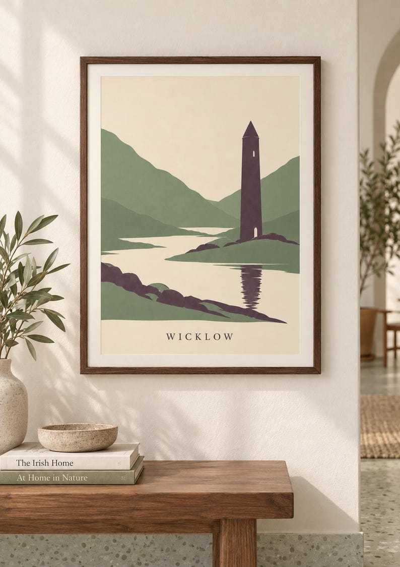 Peut inclure: Une affiche encadr&eacute;e repr&eacute;sentant une illustration de paysage stylis&eacute;e avec une haute tour violet fonc&eacute; situ&eacute;e pr&egrave;s d'une rivi&egrave;re, entour&eacute;e de collines vertes. Le mot WICKLOW est imprim&eacute; en lettres capitales noires au bas de l'affiche cr&egrave;me.