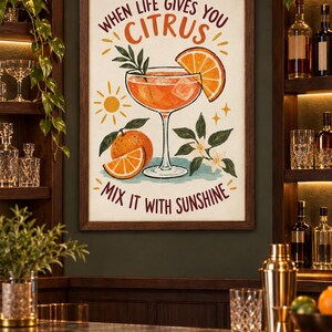 May include: A framed wall art print featuring a cocktail in a stemmed glass with an orange slice, a whole orange, and orange blossoms. The text reads, "WHEN LIFE GIVES YOU CITRUS MIX IT WITH SUNSHINE." The illustration uses orange, green, and brown tones.