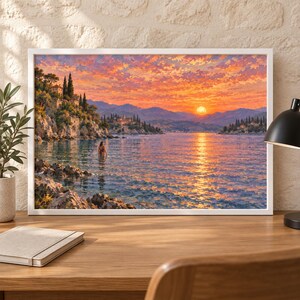 May include: A framed landscape painting depicting a coastal scene at sunset with vibrant orange and pink clouds over a calm sea. A person stands in the water near rocky cliffs and Mediterranean-style buildings, with mountains visible in the distance.