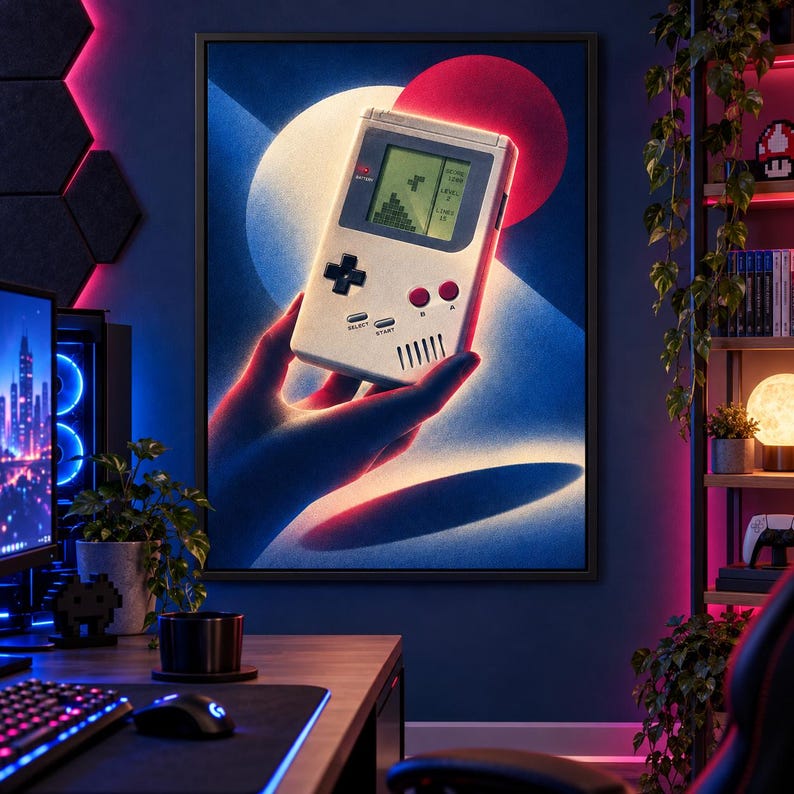 May include: A framed wall art print featuring a stylized illustration of a handheld gaming console with a monochrome screen displaying a block puzzle game. The console is held against a background of blue and red circular light gradients.
