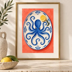 May include: A framed art print featuring a white oval platter with a blue octopus illustration and a yellow lemon slice. The platter is decorated with blue floral motifs along the rim and is set against a vibrant, solid coral-orange background.