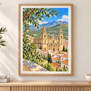 May include: A framed vertical wall art print depicting a sunlit Spanish cathedral with two towers, surrounded by white buildings with terracotta roofs, olive tree branches in the foreground, and distant mountains under a bright blue sky.
