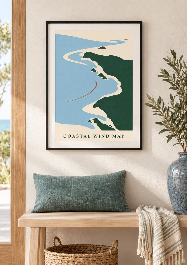May include: A framed wall art print titled COASTAL WIND MAP featuring a stylized illustration of a coastline with dark green land, light blue water, and a thin red curved line. The print is displayed in a thin black frame on a neutral wall.
