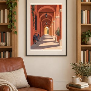 Pu&ograve; includere: Una stampa artistica incorniciata che raffigura un porticato color terracotta illuminato dal sole con una bicicletta blu appoggiata a una colonna. La scena presenta lanterne sospese, una pianta in vaso e un edificio in lontananza.