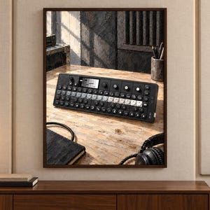 K&ouml;nnte beinhalten: Ein schwarzer tragbarer Synthesizer mit einem zentralen Display, einem Raster aus runden Tasten und mehreren Drehreglern. Das Ger&auml;t befindet sich auf einer hellen Holzoberfl&auml;che, begleitet von einem schwarzen Notizbuch und Kopfh&ouml;rern.
