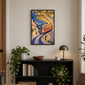 K&ouml;nnte beinhalten: Ein gerahmter Kunstdruck, der eine orangefarbene Vintage-Stra&szlig;enbahn zeigt, die in der D&auml;mmerung auf Schienen durch eine K&uuml;stenstadt f&auml;hrt. Ein gro&szlig;er Baum mit gelben Zitronen h&auml;ngt &uuml;ber der Bahn, im Hintergrund sind wei&szlig;e Geb&auml;ude und das Meer zu sehen.