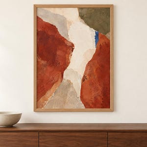 May include: A rectangular framed wall art piece featuring an abstract composition with large blocks of deep red, cream, and muted olive green, accented by a small vertical stroke of bright blue, all enclosed within a light-toned wooden frame.