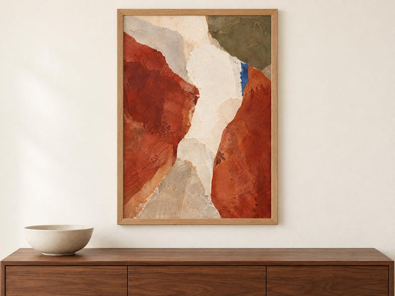 May include: A rectangular framed wall art piece featuring an abstract composition with large blocks of deep red, cream, and muted olive green, accented by a small vertical stroke of bright blue, all enclosed within a light-toned wooden frame.