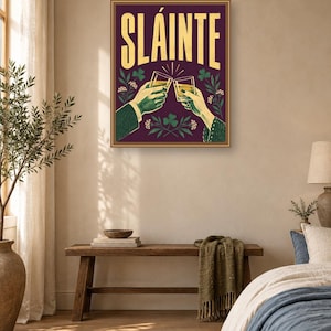 Pu&ograve; includere: Una stampa artistica da parete rettangolare con sfondo viola scuro e la parola SL&Aacute;INTE in grandi lettere gialle nella parte superiore. L'illustrazione raffigura due mani che brindano con bicchieri pieni di liquido dorato, circondate da trifogli verdi.