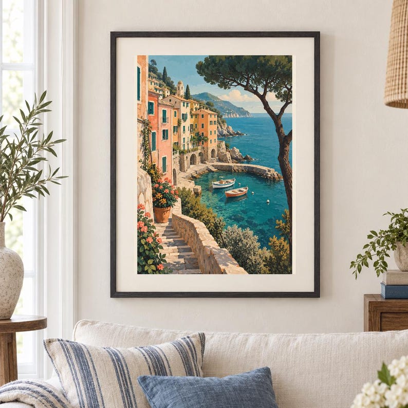 May include: A framed wall art print depicting a coastal Mediterranean village with pastel-coloured buildings, a stone staircase leading down to the turquoise sea, two small boats floating in the water, and a large tree framing the right side.