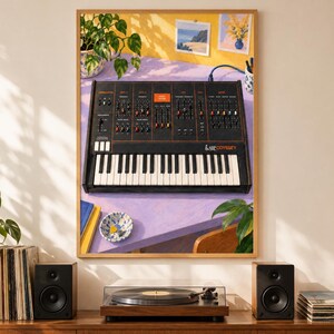 May include: A framed wall art print featuring a black ARP Odyssey analog synthesizer with orange text and knobs, set on a light purple desk. The synthesizer has a white and black keyboard, multiple sliders, and switches, displayed in a room setting.