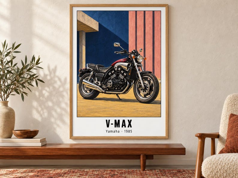 May include: A framed wall art print featuring a 1985 Yamaha V-Max motorcycle in red and black. The motorcycle is parked on a yellow surface against a blue and pink geometric background. The text V-MAX and Yamaha 1985 is printed below the image.