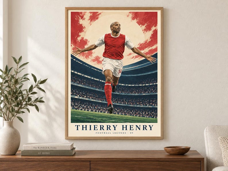 Może przedstawiać: Oprawiony plakat przedstawiający piłkarza w czerwono-białym stroju z rozłożonymi ramionami na tle stadionu i czerwonego nieba. Tekst na dole brzmi THIERRY HENRY oraz FOOTBALL LEGENDS 09 i jest napisany ciemnoniebieską czcionką.