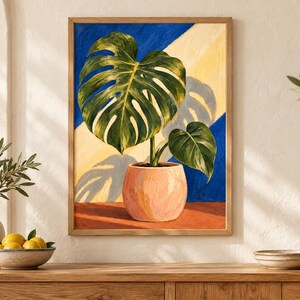 Puede incluir: Un cuadro enmarcado de una planta monstera verde en una maceta color melocot&oacute;n. El fondo presenta rayas diagonales de color azul oscuro y amarillo p&aacute;lido, con una sombra de las hojas de la planta proyectada sobre la secci&oacute;n amarilla.