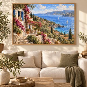 May include: A framed landscape painting depicting a Mediterranean coastal scene with a white stone villa, vibrant pink bougainvillea, and a blue sea with sailboats. The artwork features a terrace, lush greenery, and a distant hillside town under a blue sky.