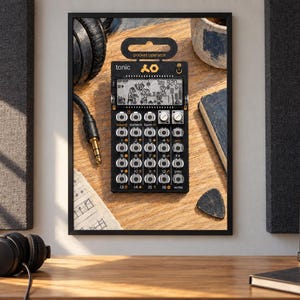 May include: A black Teenage Engineering PO-32 Tonic pocket operator synthesizer featuring a monochrome LCD screen with animated graphics, sixteen numbered buttons, two silver rotary knobs, and the text "tonic" and "pocket operator" printed on top.