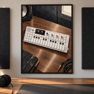 May include: A white portable synthesiser with a keyboard, multiple circular knobs, and a small digital display screen. The device features a grid of buttons, a speaker grille, and the text OP-1 printed on the right side of the rectangular chassis.