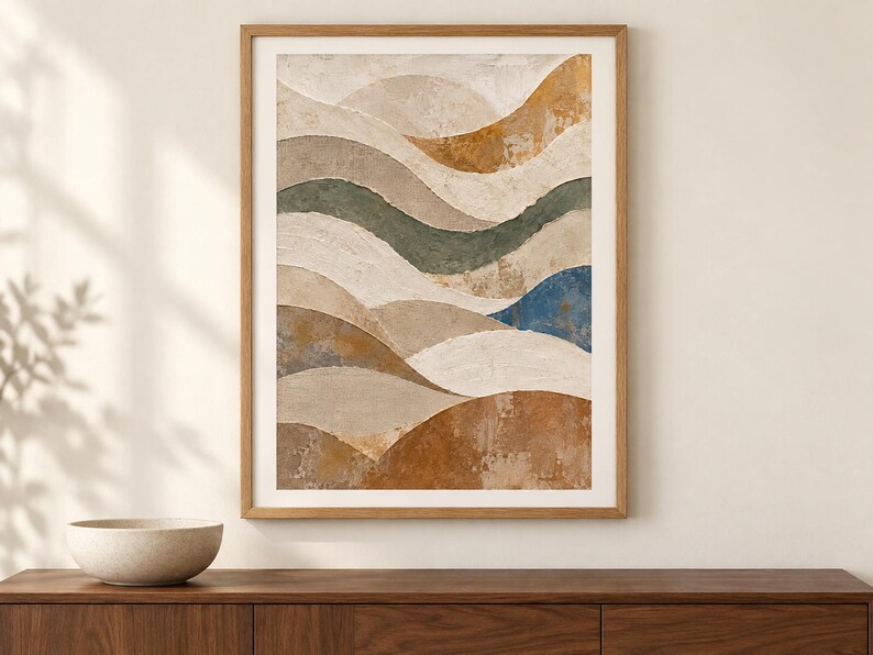 Pu&ograve; includere: Una stampa d'arte incorniciata raffigurante un paesaggio astratto con bande ondulate sovrapposte nei colori crema, beige, verde tenue, blu profondo e marrone terra. La composizione ha un aspetto materico e dipinto in una cornice di legno chiaro.