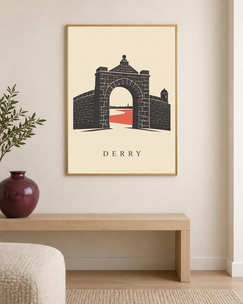 May include: A framed wall art print featuring a stylized illustration of a stone archway and city walls in dark gray against a cream background. A red path leads through the archway toward a distant horizon. The word DERRY is printed in black.