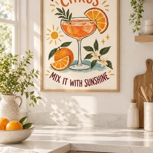May include: A framed wall art print featuring a cocktail glass filled with an orange liquid, ice cubes, and a citrus slice. The text reads, "WHEN LIFE GIVES YOU CITRUS MIX IT WITH SUNSHINE." The illustration includes a whole orange, leaves, and a sun.