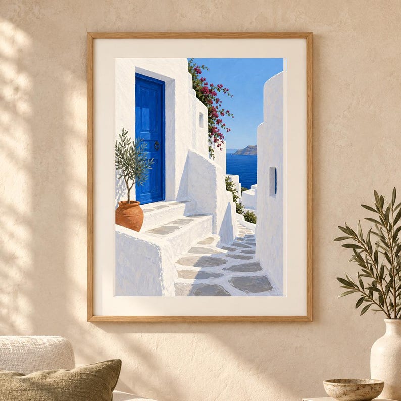 Puede incluir: Una l&aacute;mina de arte enmarcada que representa una escena mediterr&aacute;nea con edificios de piedra blanca, una puerta azul brillante y una maceta de terracota con un olivo. Flores de buganvilla rosa cuelgan sobre los muros blancos, vista al mar.