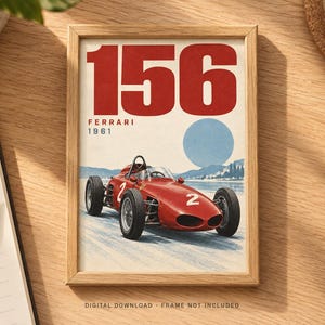May include: A framed print featuring a red 1961 Ferrari 156 race car with the number 2 on its side. The artwork displays the text 156, FERRARI, and 1961 above the car, set against a light background with a blue circle representing the sun.