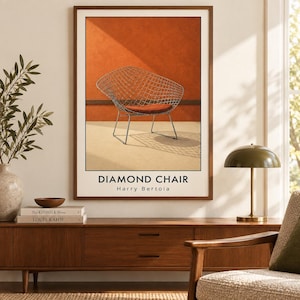 May include: A framed wall art print featuring a wire mesh Diamond Chair by Harry Bertoia. The artwork displays a metallic wire chair with a rust-colored seat cushion against a burnt orange wall and a light beige floor, with the text DIAMOND CHAIR.