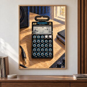 May include: A black Teenage Engineering PO-128 Mega Man pocket operator synthesizer featuring a digital LCD screen, sixteen circular buttons, two silver knobs, and the text "MEGAMAN" printed in blue above the display on a wooden surface.