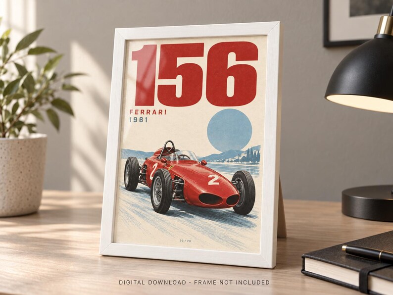 May include: A framed print featuring a red 1961 Ferrari 156 race car with the number 2 on its side. The artwork displays the text 156, FERRARI, and 1961 against a light background with a blue circular shape and a landscape illustration below the car.