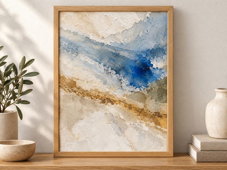 Puede incluir: Una impresi&oacute;n de arte mural abstracto enmarcada con capas texturizadas de crema, beige y bronceado, contrastadas por un audaz lavado de acuarela azul profundo que fluye diagonalmente a trav&eacute;s de la composici&oacute;n, en un marco de madera clara.