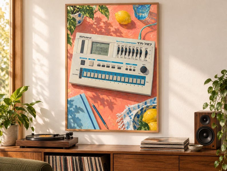 May include: A framed art print featuring a Roland TR-727 Rhythm Composer drum machine on a coral-coloured surface. The illustration includes a lemon, a blue glass of water, a blue notebook with a pen, and a bowl with lemons on a patterned cloth.