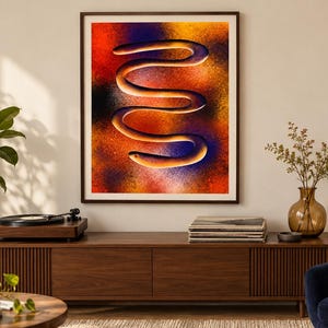 Puede incluir: Una impresi&oacute;n de arte mural enmarcada que presenta una forma serpentina horizontal central con una superficie lisa y clara. El fondo es un degradado texturizado y vibrante de rojo, naranja, amarillo y morado intenso, creando un efecto visual.