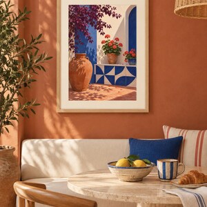Pu&ograve; includere: Una stampa d'arte da parete incorniciata che raffigura una scena mediterranea con una grande anfora in terracotta, gerani in vaso e piastrelle geometriche blu e bianche su una parete bianca, con ombre profonde e colori vivaci sotto la luce.